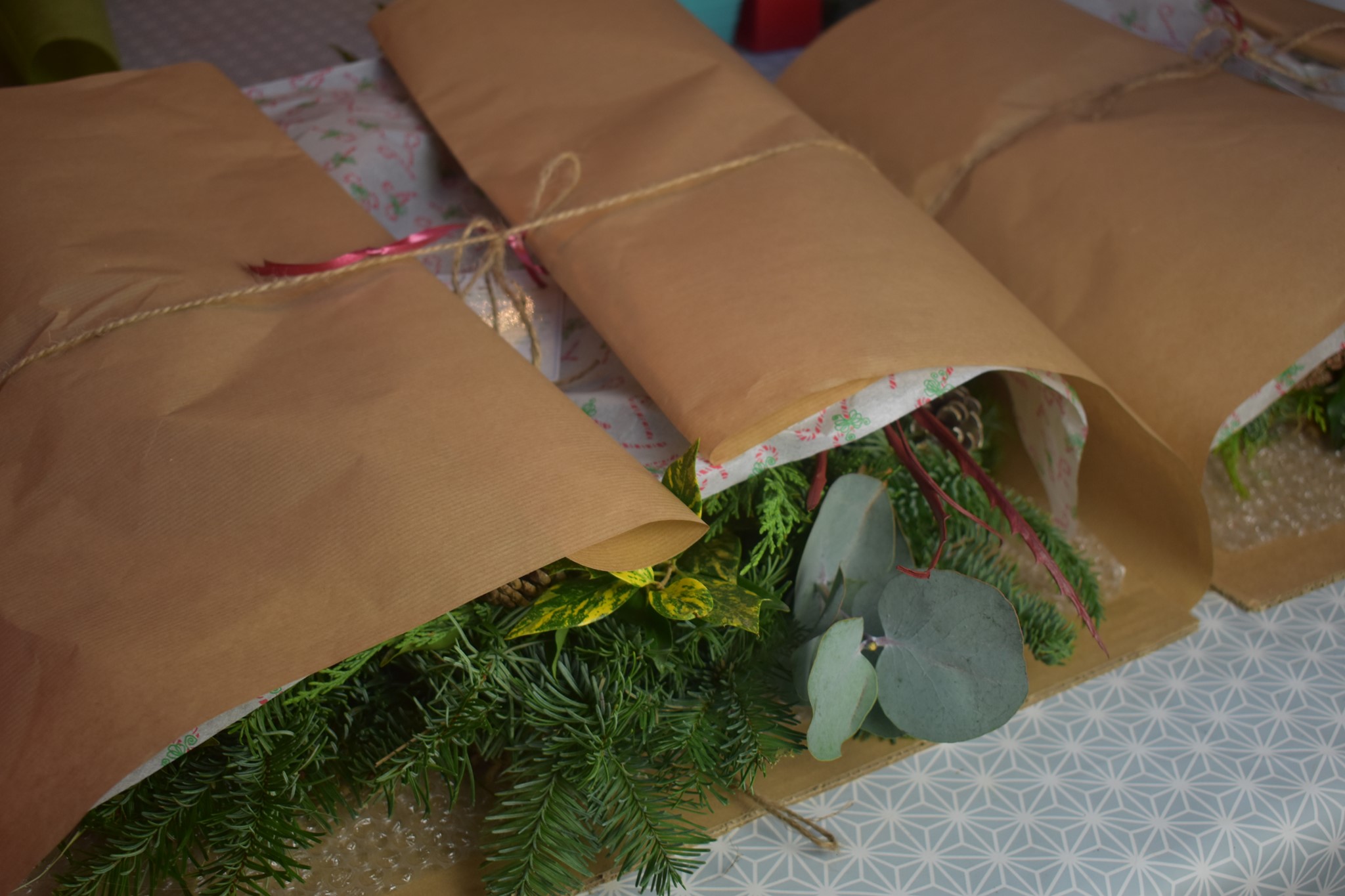 Wrapped flower bouquets in kraft paper with twine, ready for delivery, with fresh greenery