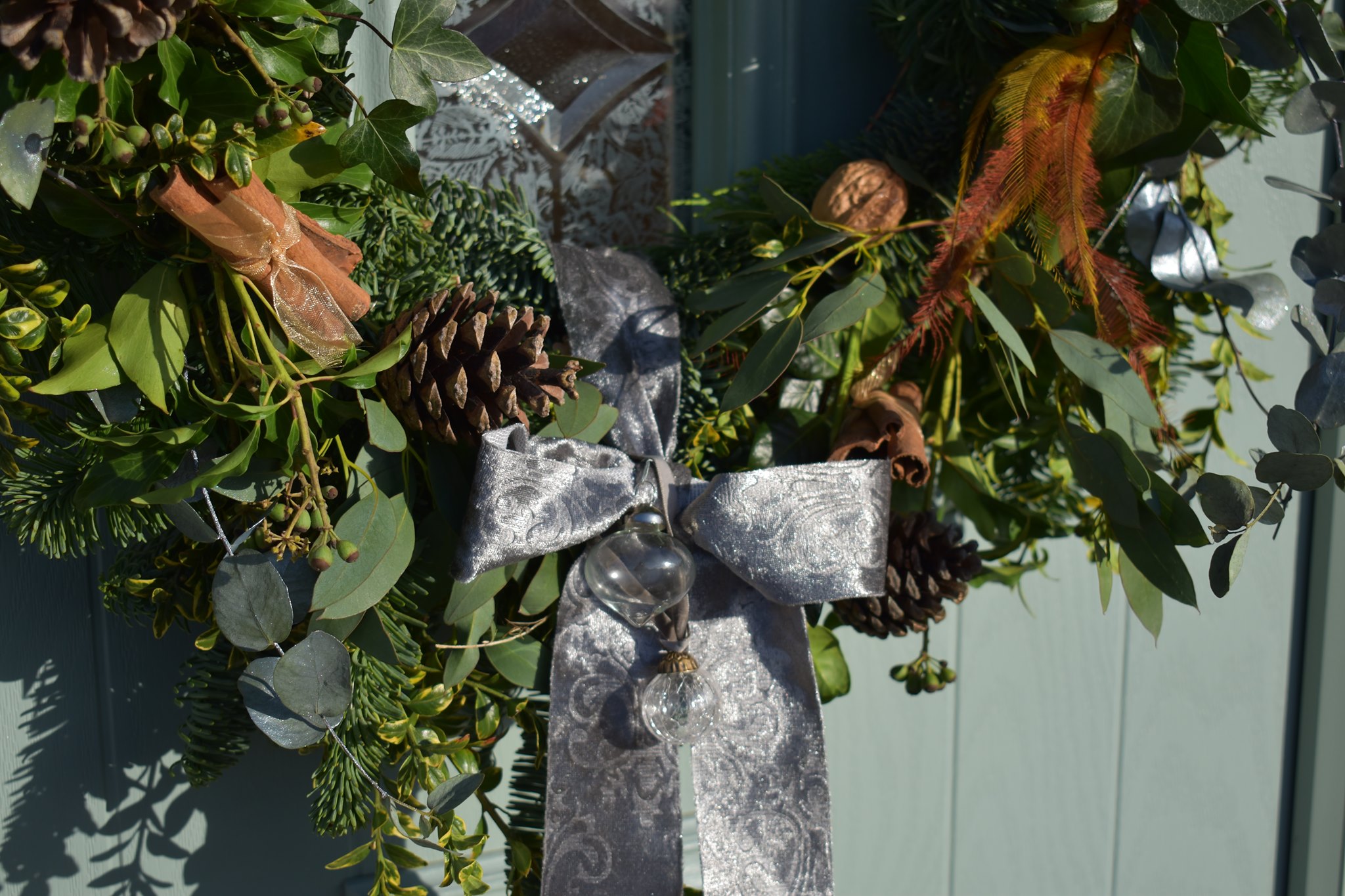 Luxurious holiday wreath with pinecones, eucalyptus, walnuts, and a silver ribbon bow