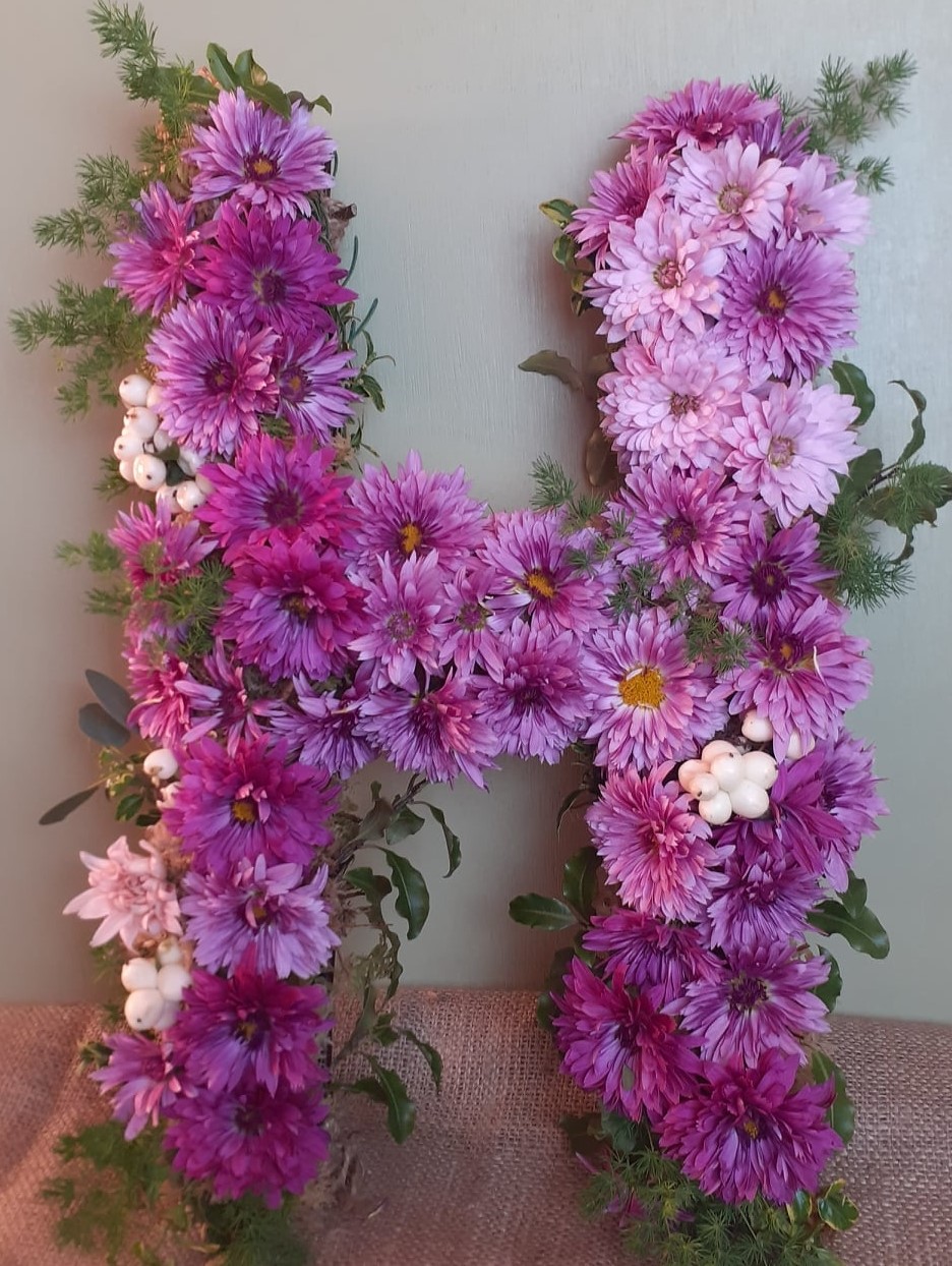 Custom floral letter made of vibrant purple chrysanthemums and greenery